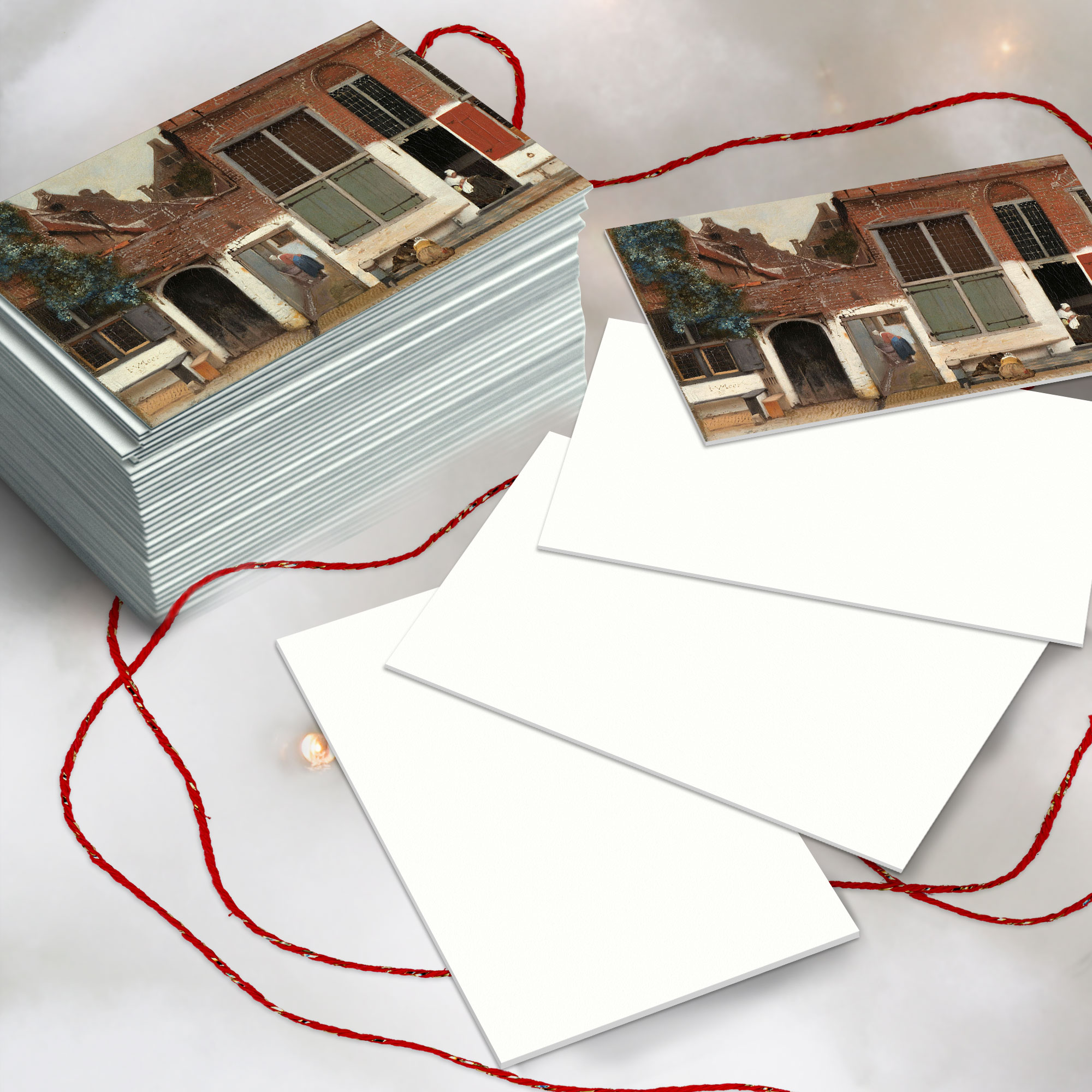 Give your Artist Something to Paint on Image ©Kimberley Hoffman Mockup from Creative Market. Image shows a sestckt of postcards on a white fluffy background with red twine and fairy lights. In addition there are four postcards spread out in front of the stack. The top image of the stack and the top image of the 4 cards is a Vermeer painting from Rijks Studio