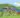 Illustration: Überarbeiteter Auszug der Rückseite von »Die Kurpfalz wimmelt«. Der Hintergrund zeigt den Neckar und den Heidelbergerschloss. Die Sonne scheint und der Himmel ist blau mit weichen Wolken. Im Vordergrund sind zehn Kindergartenkinder, die vier Kornmäuse, eine Erzieherin und einen Erzieher sowie zwei lustige Störche und zwei Spargelfiguren, die im Roten Cabriolet sitzen. Illustration ©Kimberley Hoffman