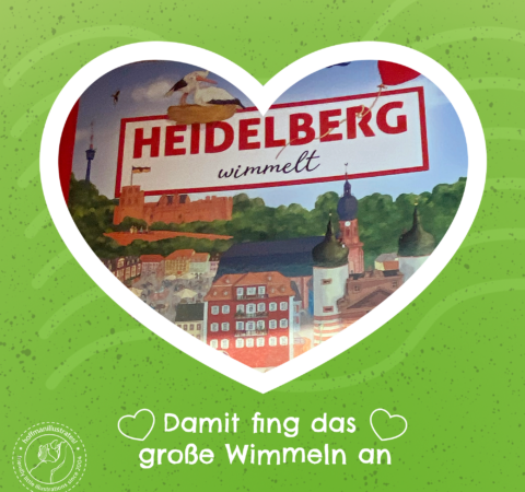 Titelseite von »Heidelberg wimmelt«, gerahmt mit einem weißen Herzen. Der Hintergrund ist grün. Der Bildtext liest: Damit fing das große Wimmeln an.